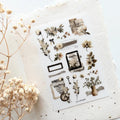 Vintage botanical transfer sticker sheet with floral illustrations, labels, frames, and neutral-toned journaling elements on textured background