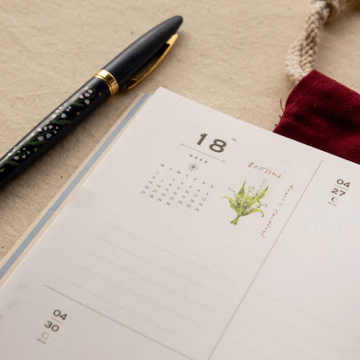 Open notebook with a calendar page and a pen on a textured surface