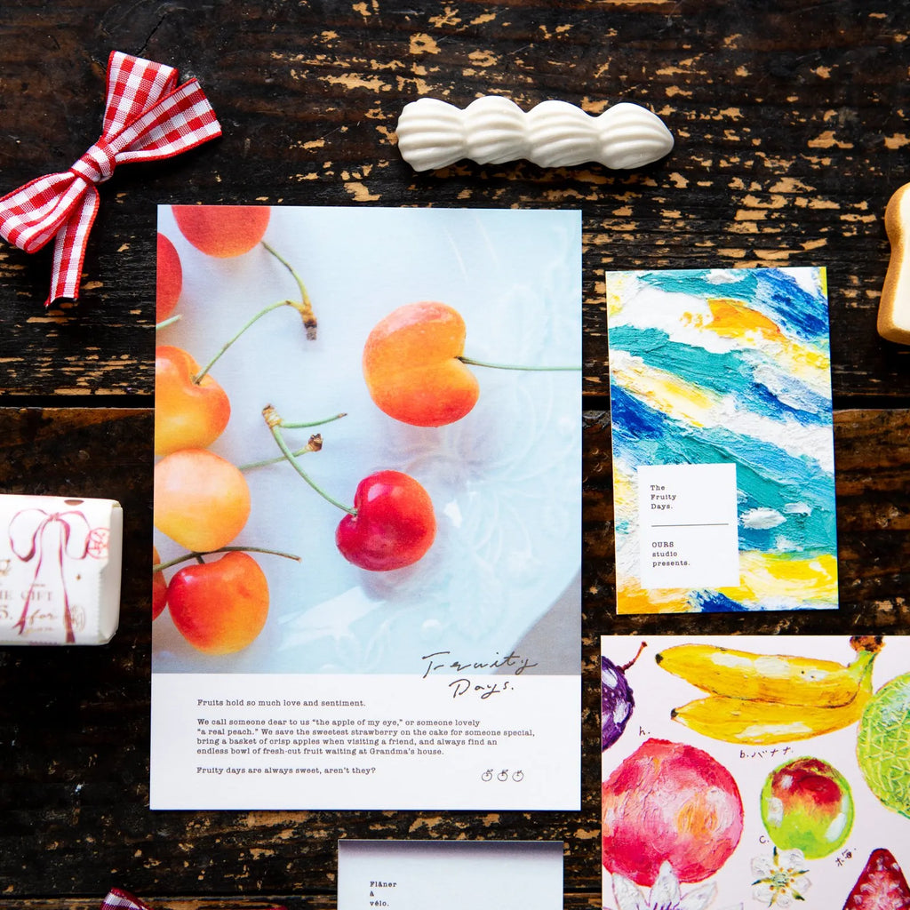 OURS Studio 2027 Journal fruit-themed invitation suite flat-lay on dark wood