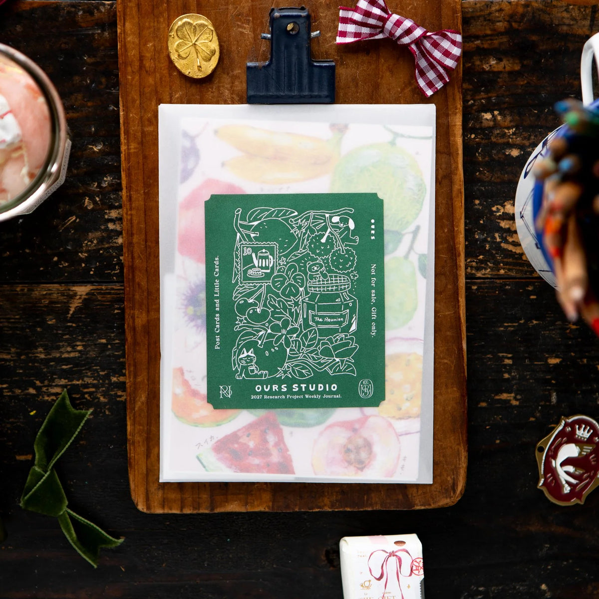 OURS Studio 2027 Journal [The Reunion], green cover flat-lay with a clover pin and mug
