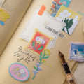 Decorative stickers with artistic designs on a notebook page with a fountain pen.