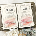 Two cards with decorative designs and Chinese text on a metal tray with flowers.