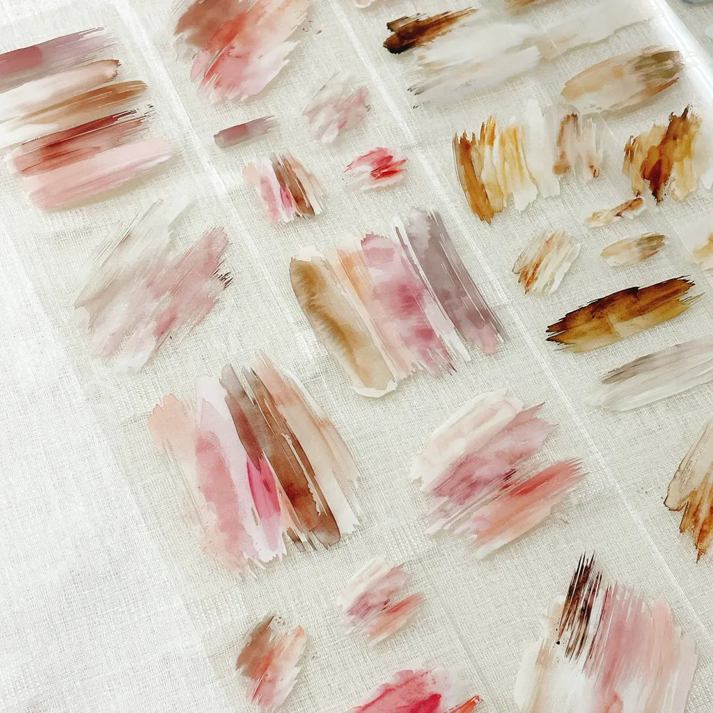Pattern of brush strokes in pink, brown, and beige on a textured white background