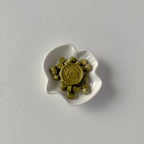 Small white dish with gold coins on a light gray background