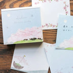 Set of stationery items with cherry blossom designs on a wooden surface
