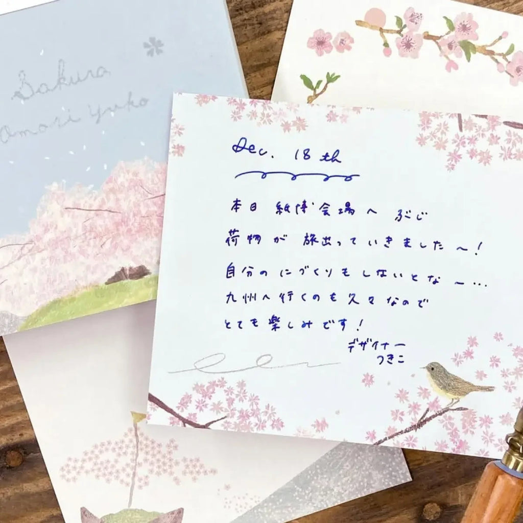 Handwritten letter with cherry blossom and bird designs on stationery