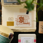 Set of rubber stamps on a wooden surface with a plant in the background