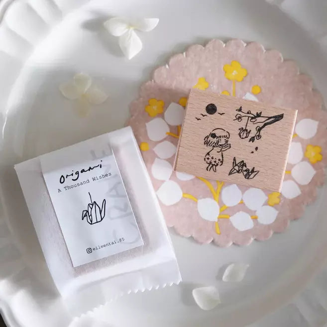 A Thousand Wishes Paper Cranes stamp with origami packaging on a floral decorative plate