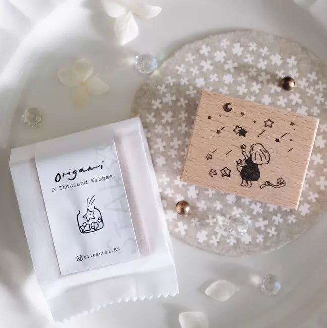 A Thousand Wishes Paper Stars stamp with star and moon designs on a white styled surface