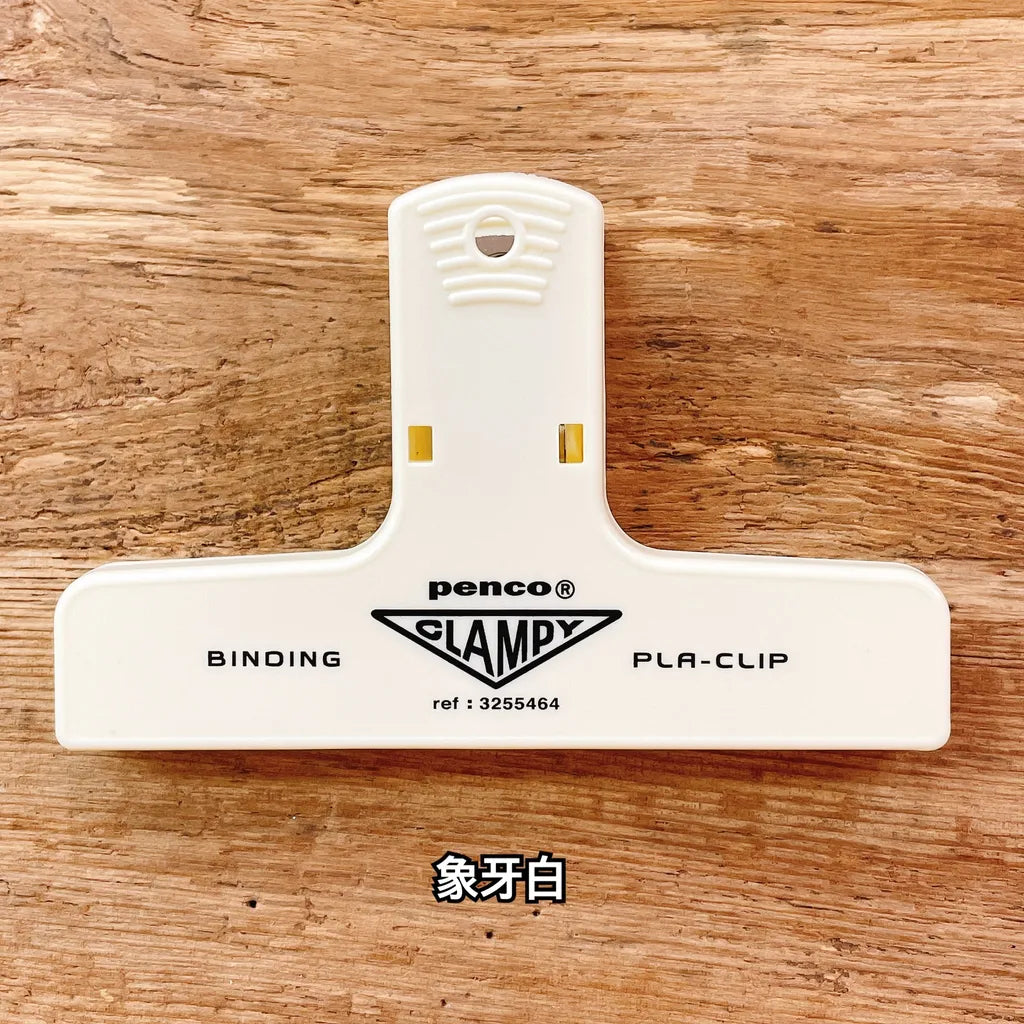 White binding clamp with 'Penco' branding on a wooden surface