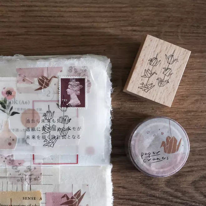 Paper Cranes Strings stamp with floral packaging, wooden block and labeled container on wood