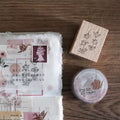 Packaging with floral designs and a wooden stamp on a wooden surface