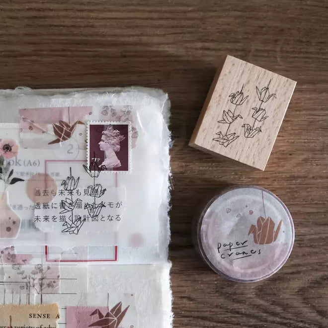 Paper Cranes Strings Rubber Stamp with its floral packaging displayed on a wooden surface