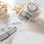Decorative tape with floral and landscape designs on a white surface with dried flowers.