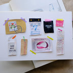 Collection of small decorative items on a white sheet of paper with a pen and other stationery items in the background.