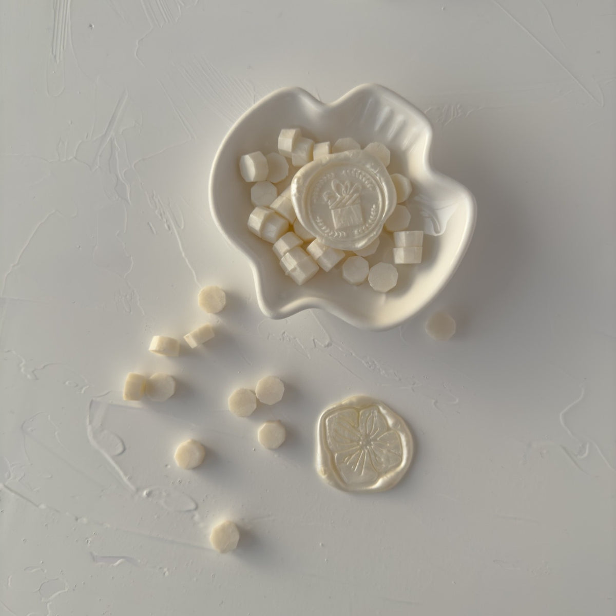 Pearl White Wax Beads in a white ceramic mold showing their small round shape on a light grey backdrop