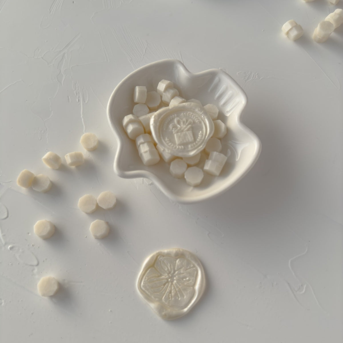 Stamped Pearl White wax seal pieces on a decorative mold showing an elegant pearly finish on grey