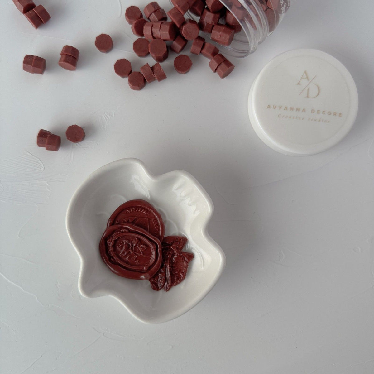 Pecan Pie Wax Beads pieces in a white dish with the storage container and lid on a light grey backdrop