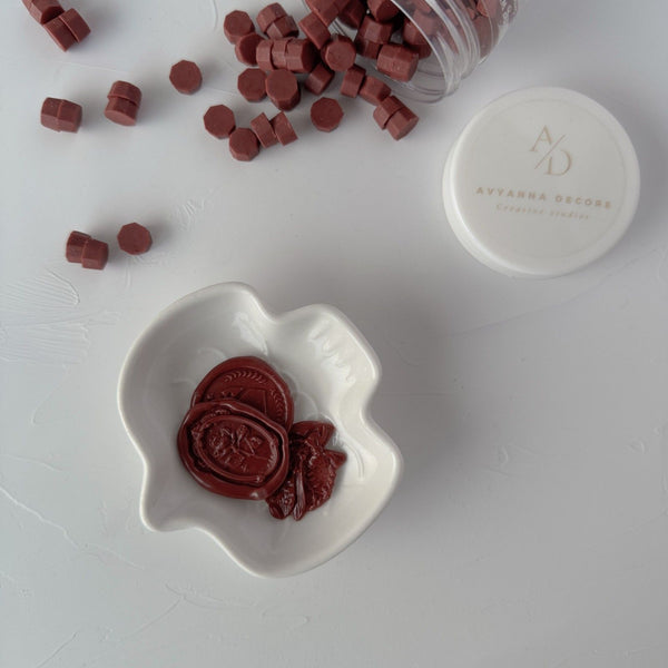 Pecan Pie Wax Beads pieces in a white dish with the storage container and lid on a light grey backdrop