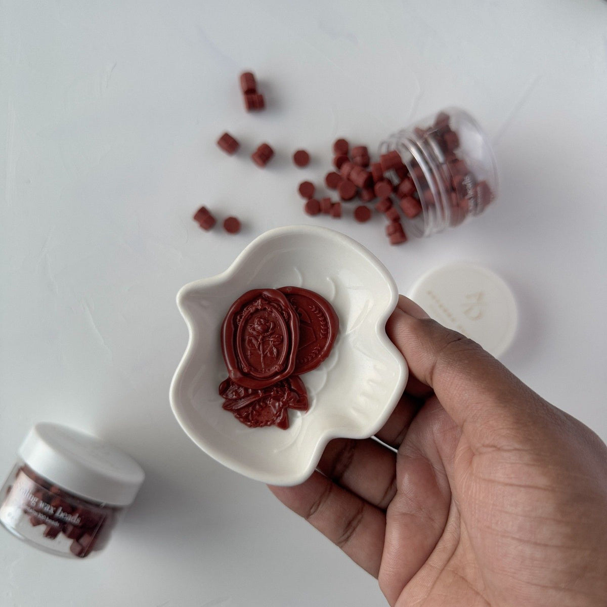 Hand holding a heart-shaped dish of Pecan Pie Wax Beads with loose beads scattered on a light surface