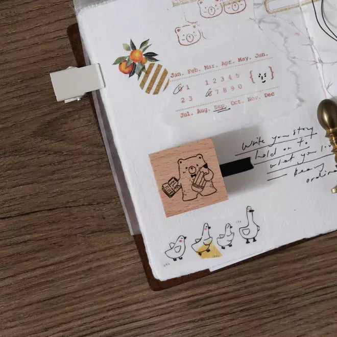 Pencil Bear Rubber Stamp with its cartoon bear design on a notebook on a wooden surface