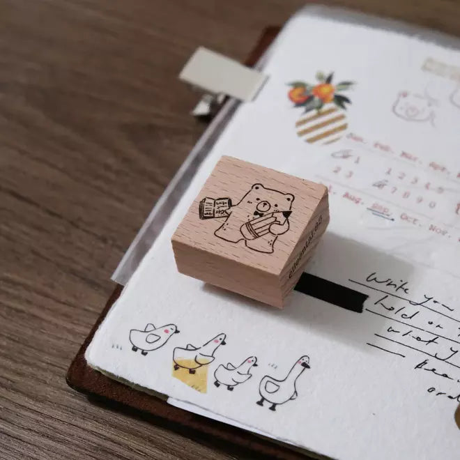 Pencil Bear wooden stamp resting on a doodle-filled notebook page, styled close-up view