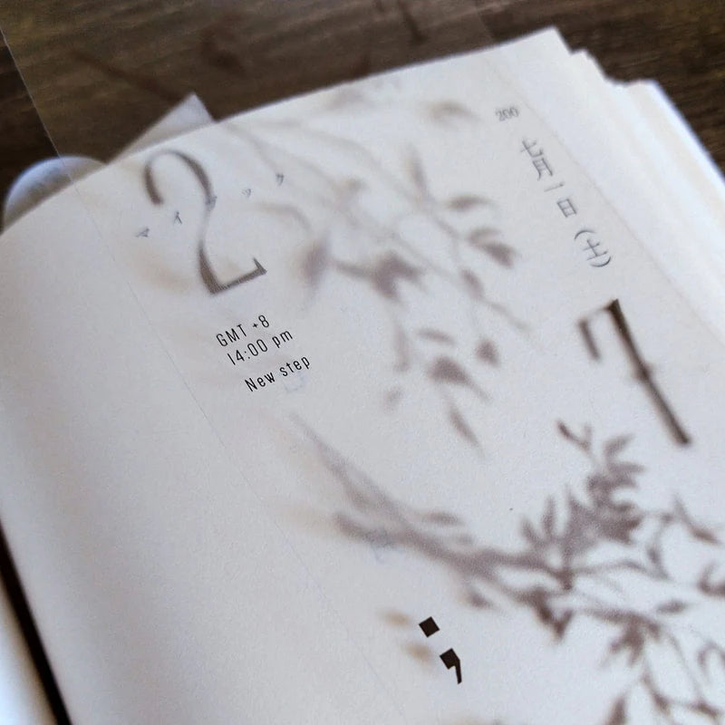 Close-up of a book styled with Penumbra Tree Shadow PET Tape botanical design on wood