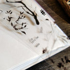 Close-up of a planner with tree design and text on a wooden surface