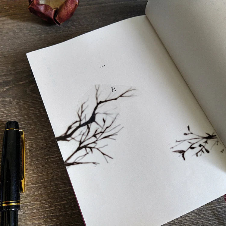 Notebook with Penumbra Tree Shadow PET Tape black ink tree designs beside a pen on wood