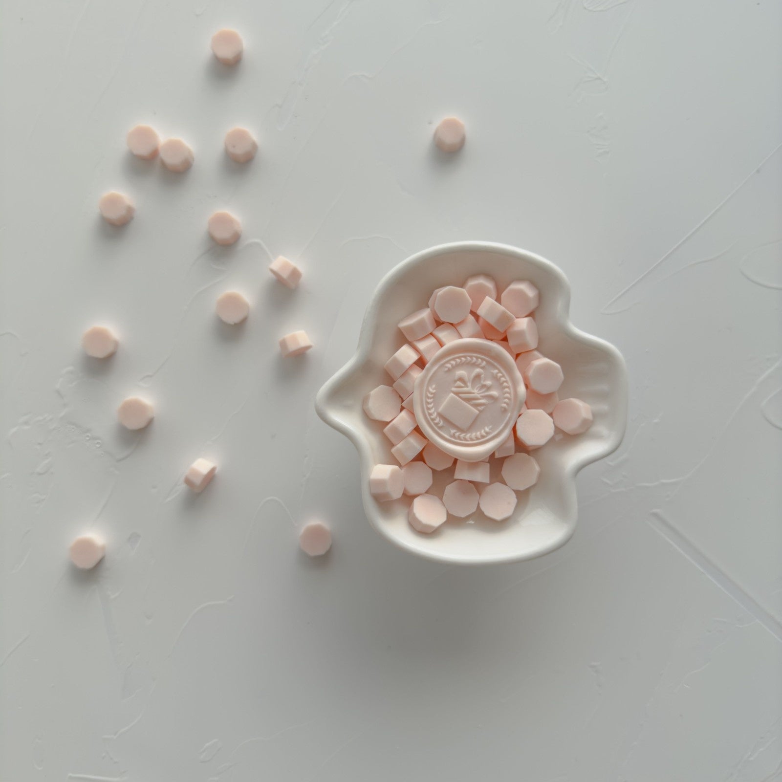 Pink candies in a white dish on a light gray surface