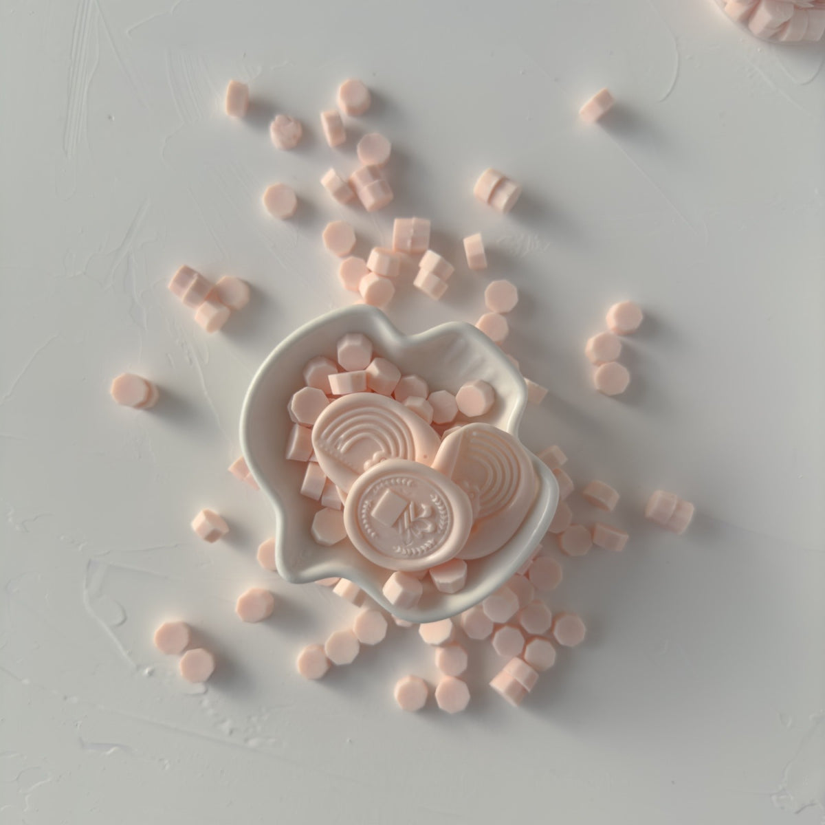 Heart-shaped Pink Flamingo sealing wax pieces with stamped logo detail on a light grey background