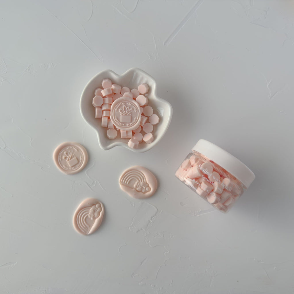 Set of pink sealing stamps and a container on a light gray background
