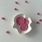 Pink cookies with a logo in a white dish on a light gray background