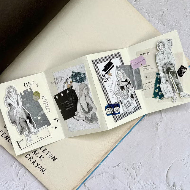 Open book styled with Black Matte PET Tape monochrome illustrated pages on a textured surface