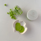 Green cookies in a jar, on a white dish, and with a container on a light gray background