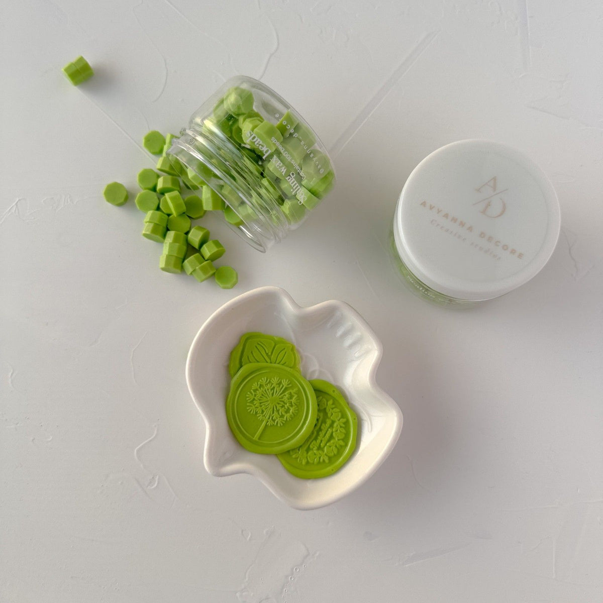 Pistachio Wax Beads shown in a jar, white dish and container together on light grey
