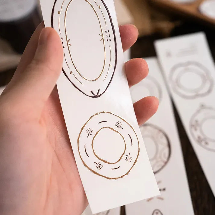 Hand holding a white card decorated with circular plate motifs from the Plates Rose Gold PET Tape
