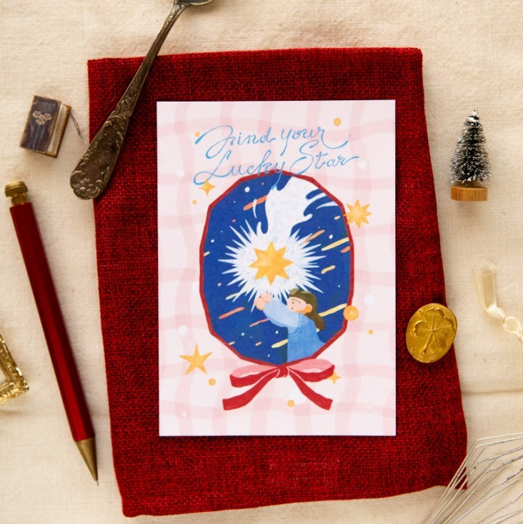 Card with a star design on a red textured surface with stationery items.