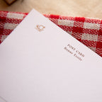 White postcard with 'POST CARD Bonne étoile' text on a red and white checkered fabric background