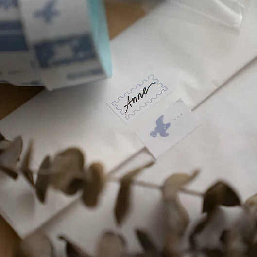 Small box with a label on a white surface with dried leaves.