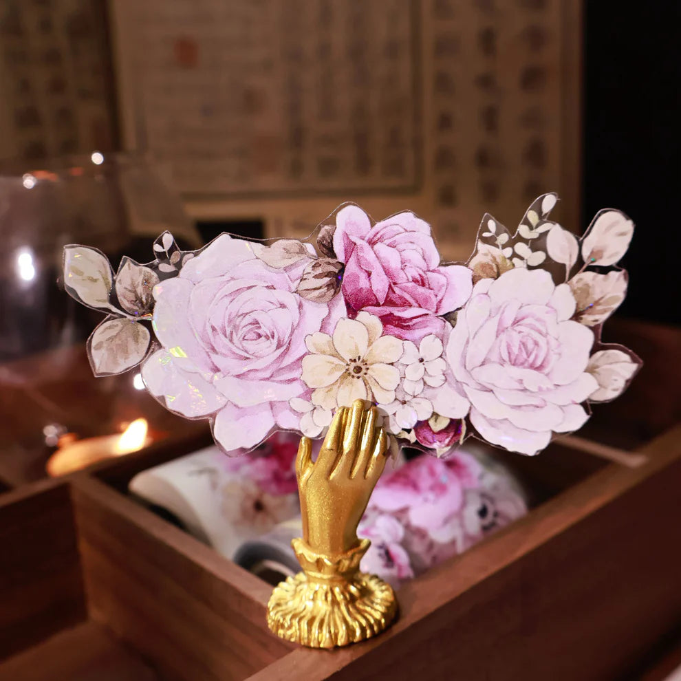 Decorative vase with pink flowers and gold base on a wooden surface