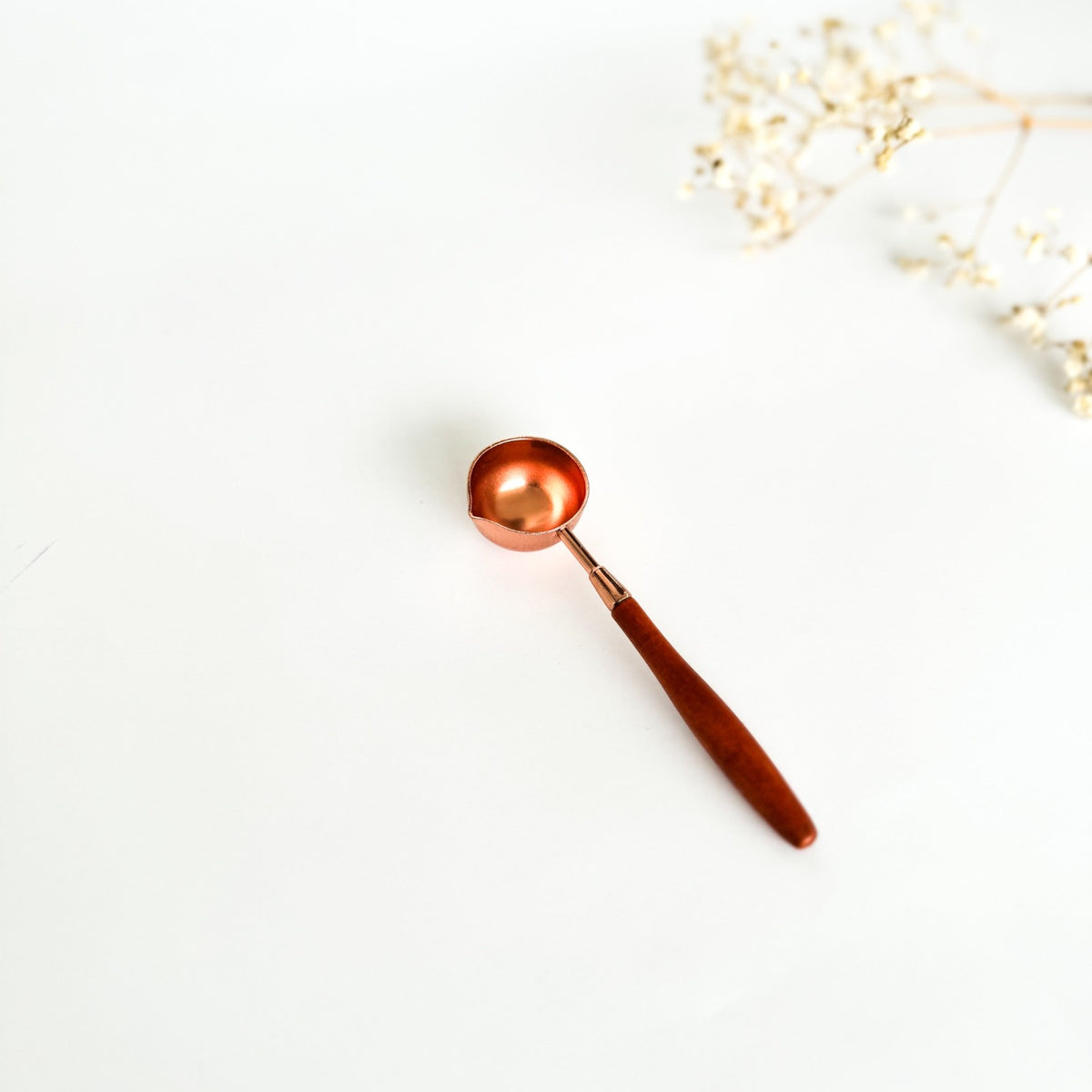 Refined Wax Spoon with copper-toned metal bowl and wooden handle on a white background