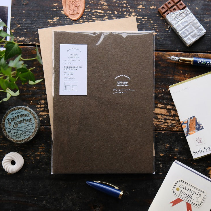 Research Notes Notebook by OURS Studio in brown with a pen and mini books on a wooden desk