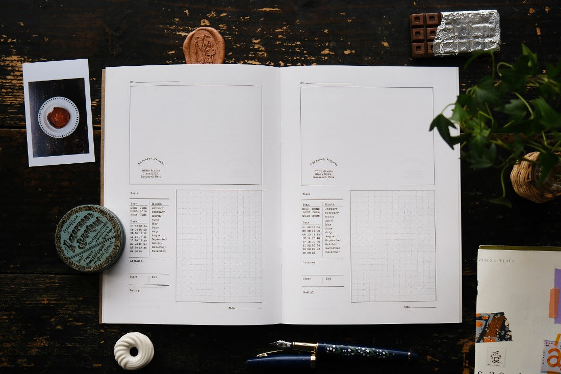 Open Research Notes Notebook styled with a pen and small deco items on a wooden surface