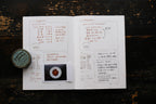 Open book with text and a small round object on a wooden surface