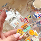 Packaged travel-themed stickers with a hand holding the packaging.