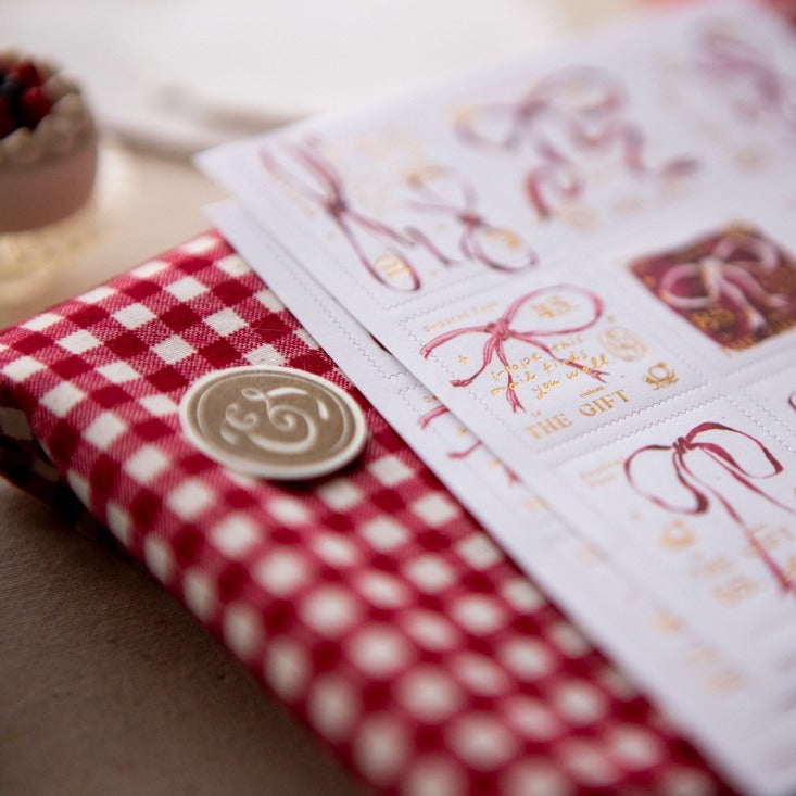 Ribbon Bow Stamp Sticker Sheet by OURS Studio — sticker-decorated book on red checked cloth, for journaling