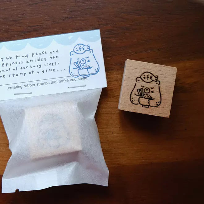 Foodie Bears Rice stamp displayed beside a small bag of tea on a warm wooden surface
