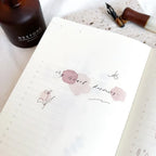 Notebook with floral design and text on a white surface with a bottle labeled 'RESTORE'.