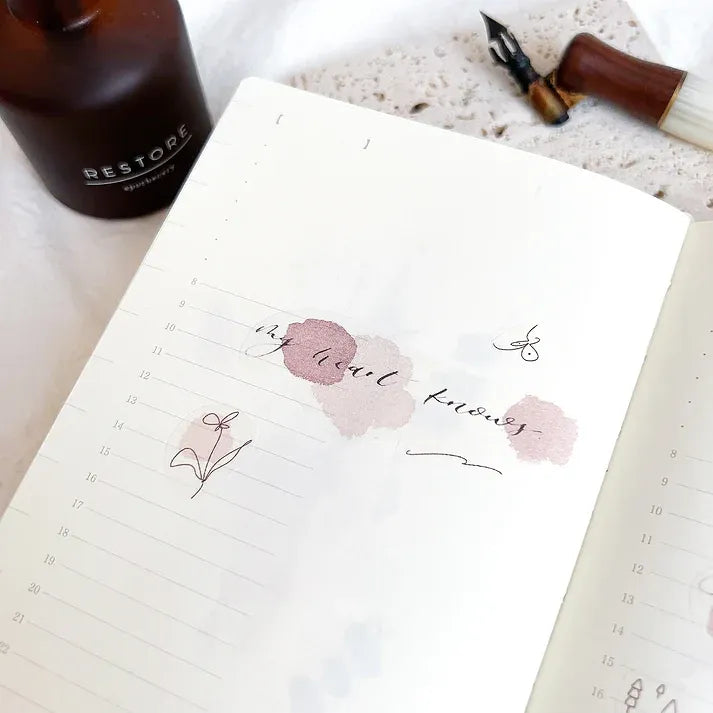 Notebook decorated with Rose Calligraphy PET Tape florals beside a Restore bottle on a white surface